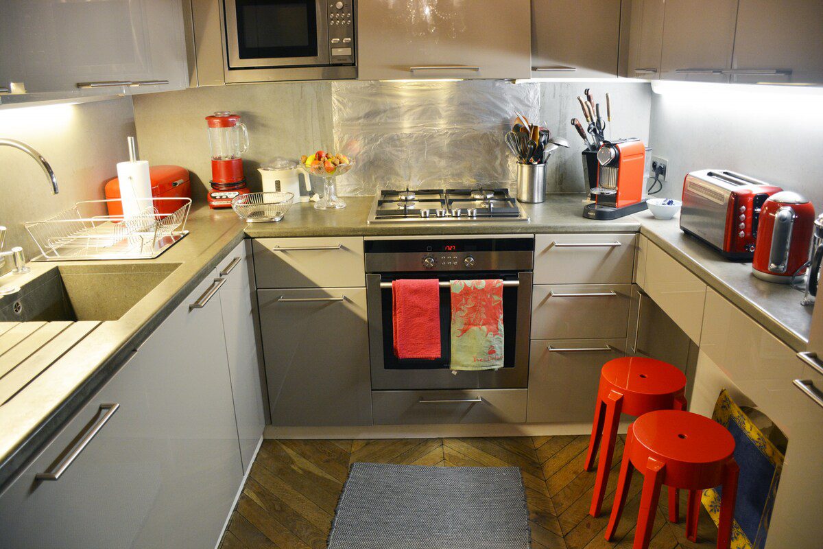 Luxury duplex near Eiffel Tower Paris – fully equipped kitchen with red stools and steel splashback