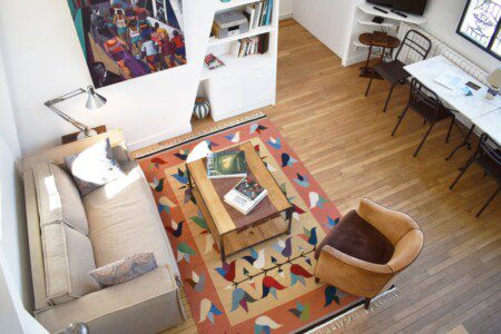 Artist loft Paris – open-plan living room with colourful geometric rug overhead view