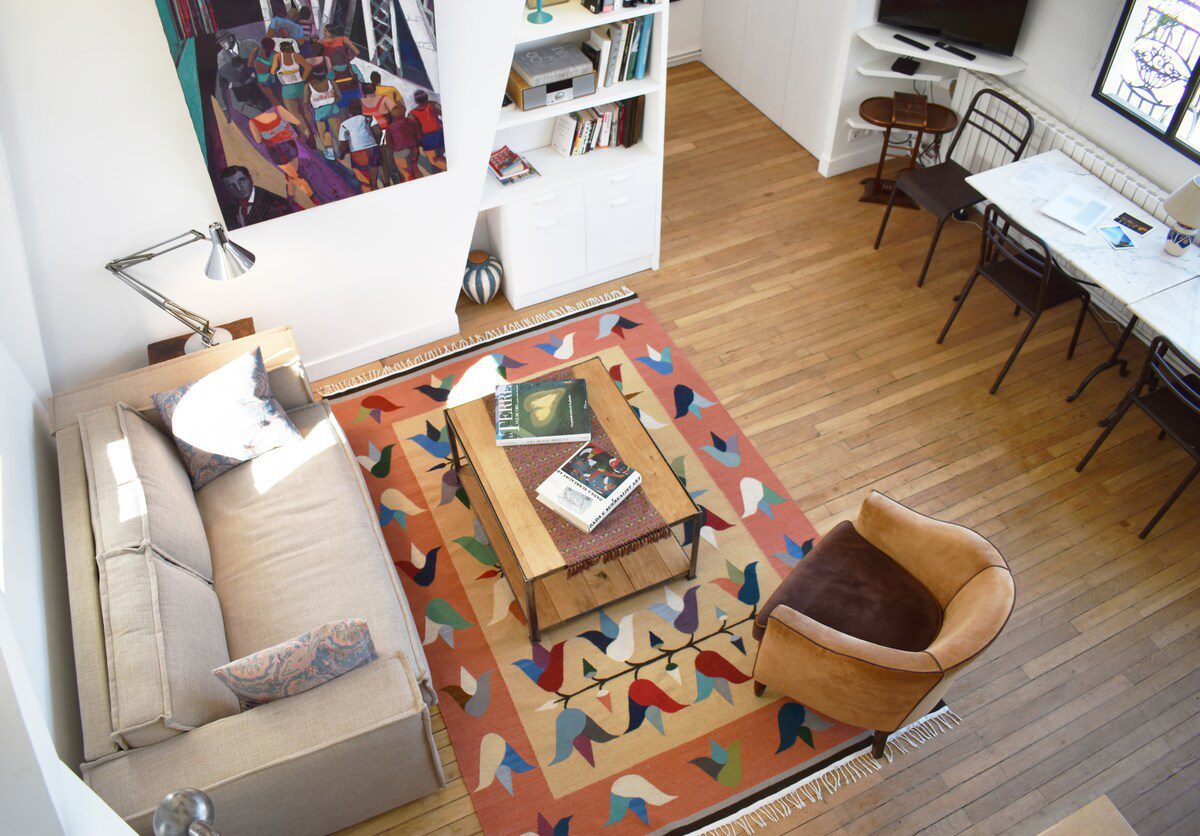 Artist loft Paris – open-plan living room with colourful geometric rug overhead view